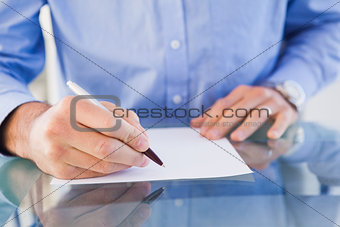 Businessman sitting at desk writing