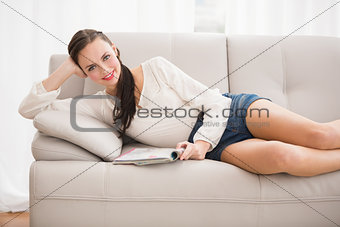 Pretty brunette reading magazine on the couch