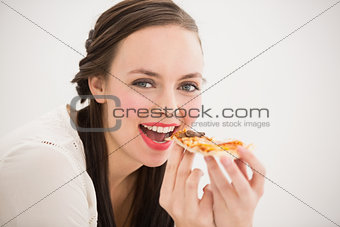 Pretty brunette eating slice of pizza