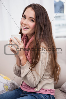 Pretty brunette having coffee on the couch