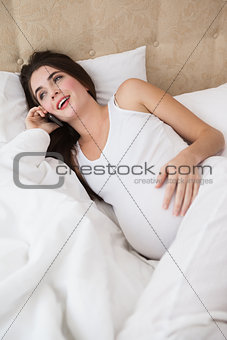 Pregnant brunette on the phone in bed