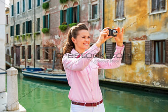 Happy young woman taking photo in venice, italy