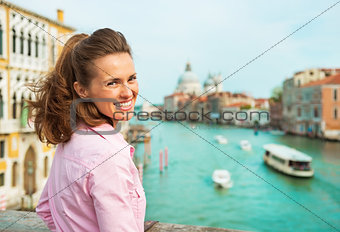 Happy young woman standing on bridge with grand canal view in ve
