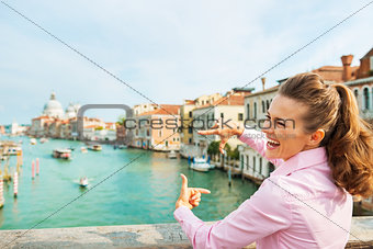 Happy young woman framing with hands while standing on bridge wi