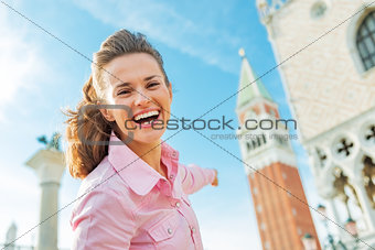 Happy young woman pointing on campanile di san marco in venice, 