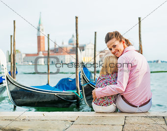 Portrait of happy mother and baby sitting on grand canal embankm