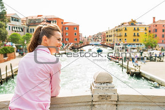 Happy young woman standing on bridge in venice, italy and lookin