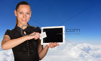 Beautiful businesswoman holding tablet PC and business card in front of screen. Blue sky with cloud layer as backdrop