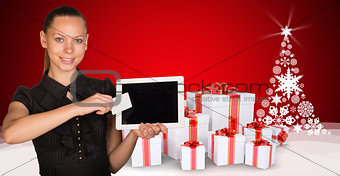 Beautiful businesswoman holding tablet PC. New Year tree and gifts as backdrop
