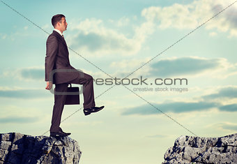 Businessman standing on the edge of rock gap