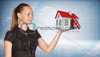 Businesswoman holding model house with tag for rent
