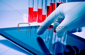 hand in medical blue glove touching modern digital tablet in laboratory