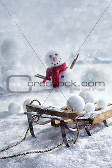 Wooden sleigh and snowballs with snowman 