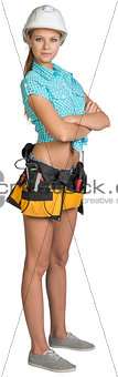 Pretty girl in helmet, shorts, shirt and tool belt with tools. Full length