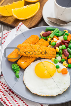 Fish sticks, fried egg and vegetables
