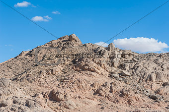 Rocky desert mountain with blue sky background