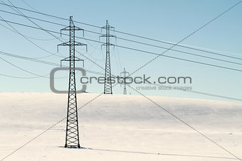 High voltage electricity power pylon on snowy field