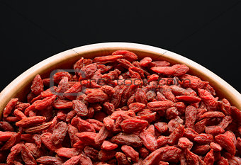 Wooden Bowl Full of Dried Goji Berries on the Black Table