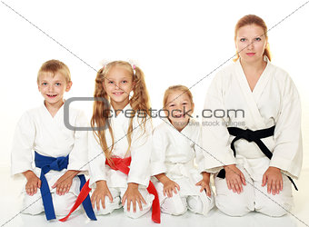 A boy with his sister and mother with her daughter sitting in a karate pose ritual