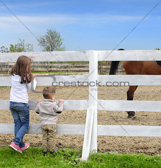 Pre-teen girl and Baby boy on the a white picket fence beside th