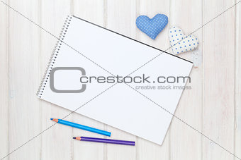 Blank paper, pencils and valentines day heart shaped toys on the