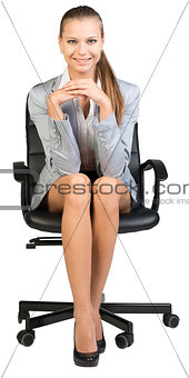 Businesswoman on office chair, with hands clasped under her chin
