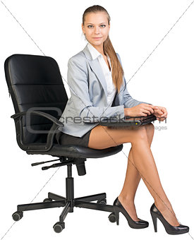 Businesswoman on office chair, holding closed laptop