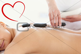 Composite image of portrait of a beautiful woman having a massage with stones