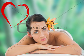Composite image of beautiful brunette relaxing on massage table smiling at camera