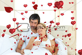 Composite image of positive couple drinking coffee lying in the bed