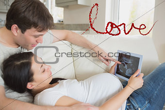 Composite image of prospective parents looking at ultrasound scan on tablet pc