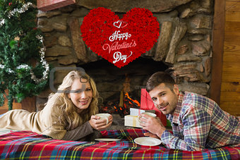 Composite image of couple with tea cups in front of lit fireplace