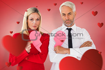 Composite image of couple not talking holding two halves of broken heart
