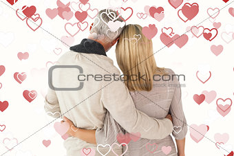 Composite image of happy couple standing with arms around