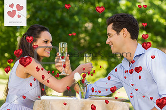 Composite image of couple with champagne flutes sitting at outdoor café