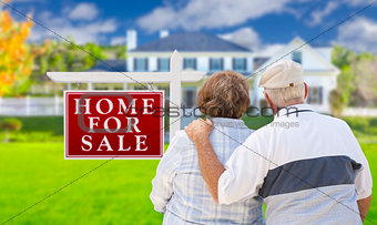 Happy Senior Couple Front of For Sale Sign and House