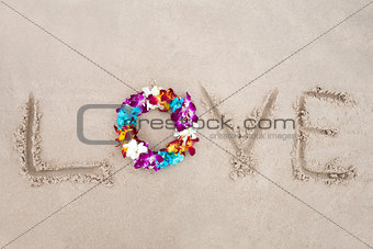 Colorful flower diadem on the sand with letters