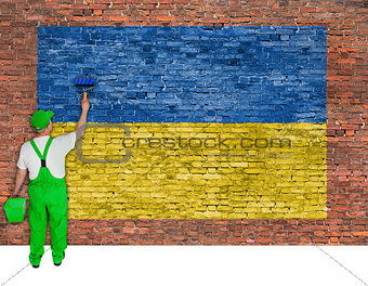 House painter paints flag of Ukraine on brick wall