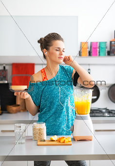 Happy fitness young woman making pumpkin smoothie in kitchen and