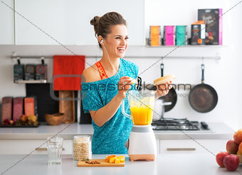 Happy fitness young woman making pumpkin smoothie in kitchen