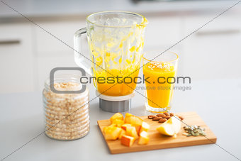 Close-up on pumpkin smoothie and ingredients on table in kitchen