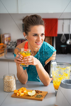 Happy fitness young woman with pumpkin smoothie in modern kitche