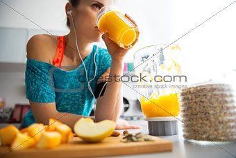 Close-up on fitness young woman drinking pumpkin smoothie in kit