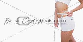Midsection of fit woman measuring waist