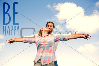 Composite image of happy couple standing outside with arms stretched kissing