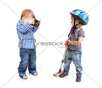 Two toddler boys playing: one boy holding a camera another posing with a mop