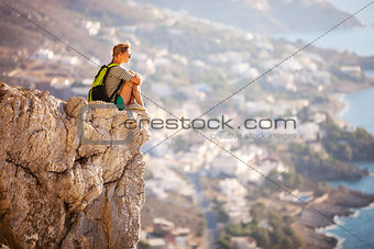 Young woman sitting on rock and enjoying beautiful view