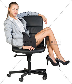 Businesswoman on office chair with her legs over armrest