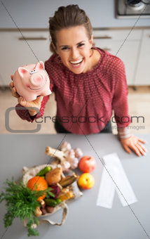 Closeup on happy young housewife showing piggy bank after local 