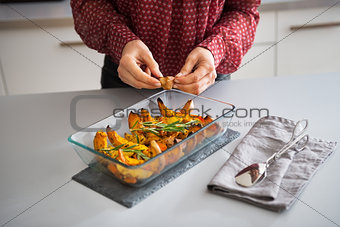 Closeup on young housewife adding garlic to baked pumpkin